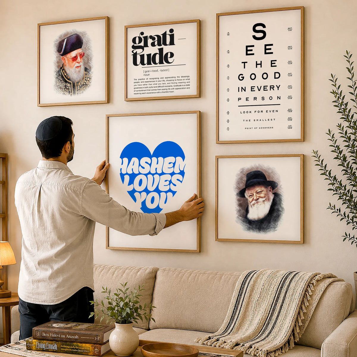 Man hanging a gallery wall of framed Jewish wall art and Gedolim portraits in a living room